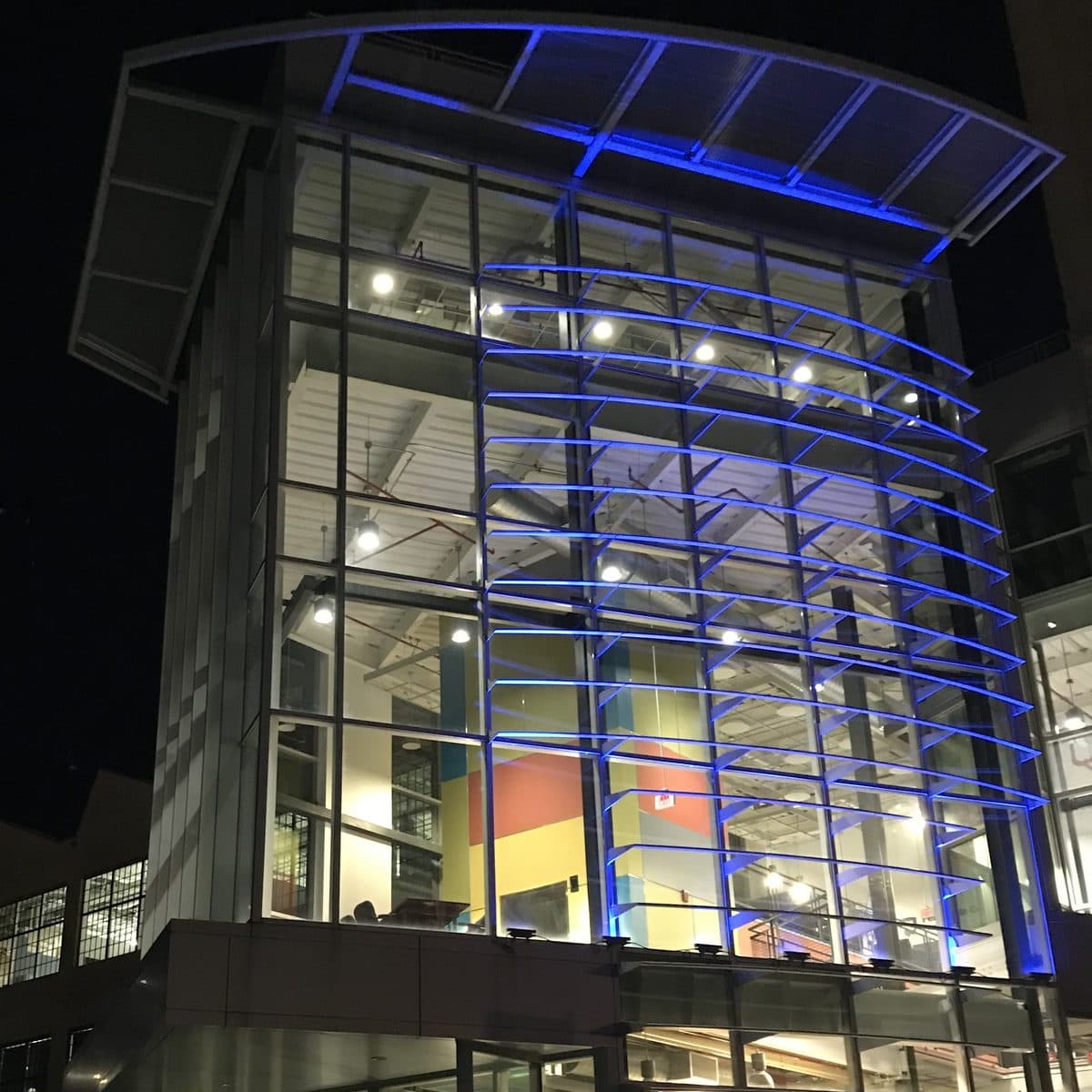 The glass atrium of the Energy Innovation Center lit blue at night
